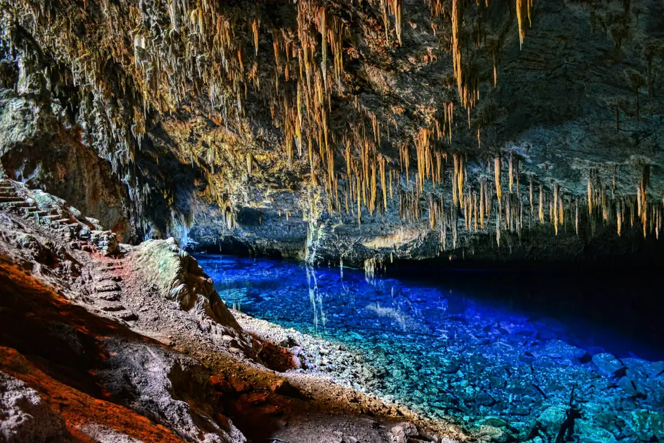 a cave filled with blue water and lots of ice hanging from the ceiling — Bonito