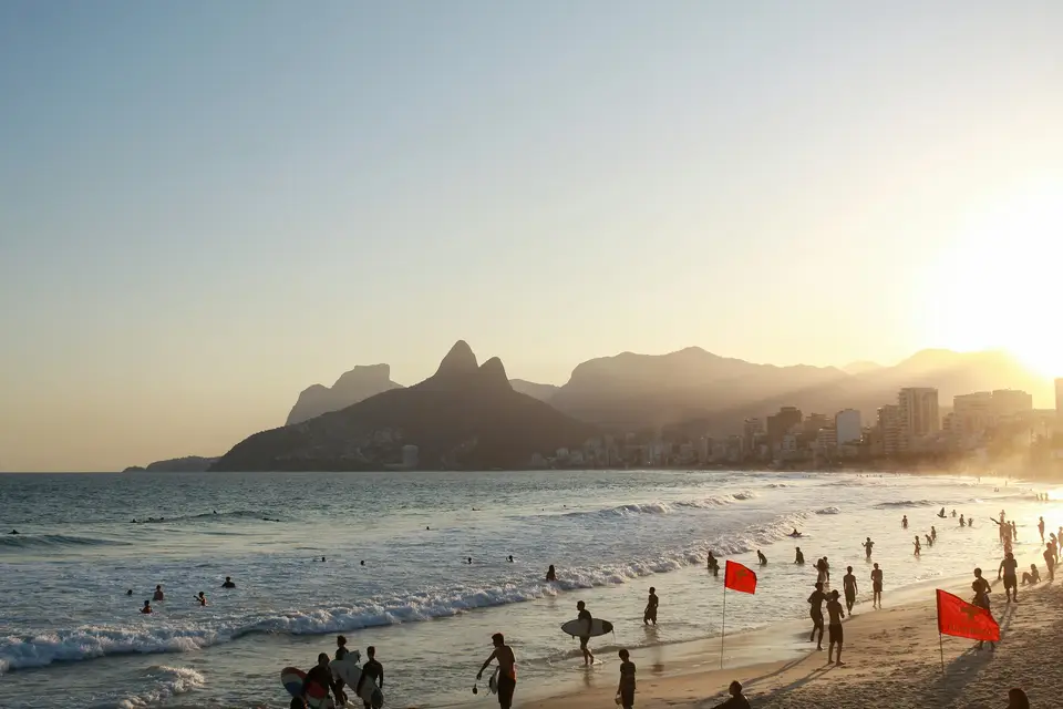 a group of people standing on top of a sandy beach — Búzios