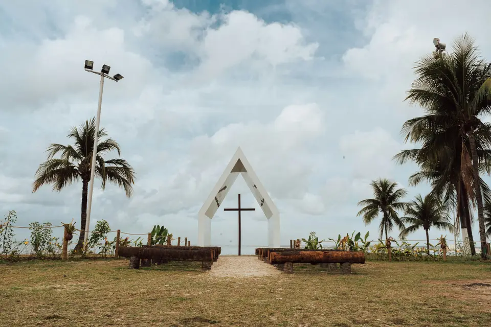 a church with a cross and benches in front of it — Maceió