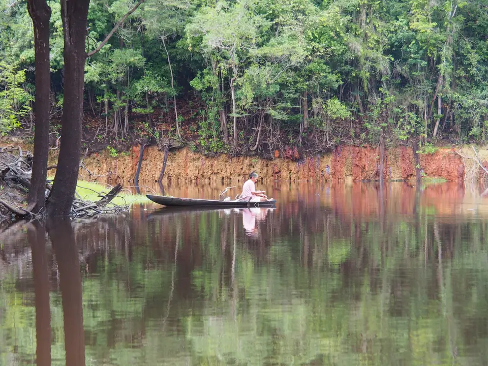 man in brown boat on lake during daytime — Manaus
