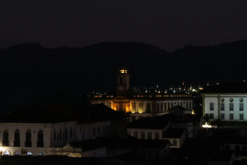 a city at night with a clock tower in the background — Ouro Preto
