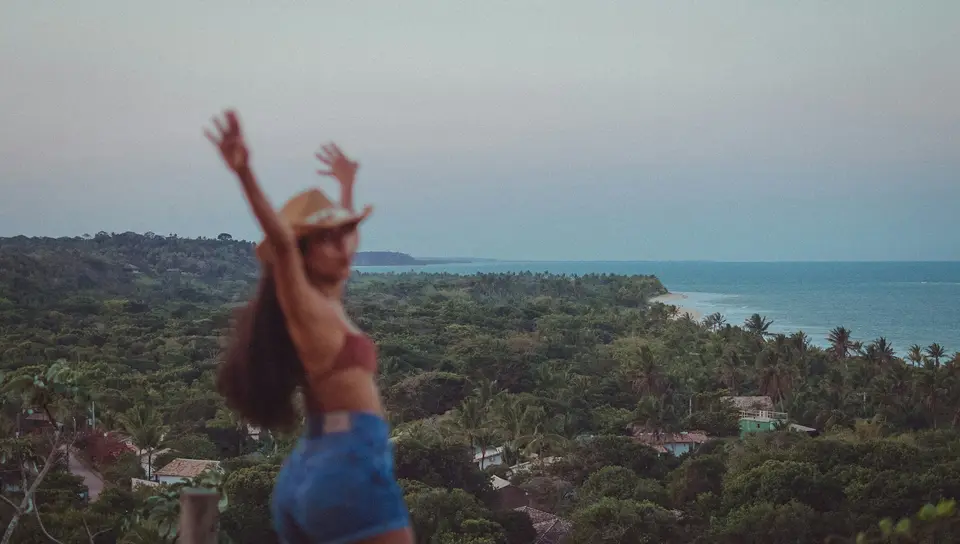 a woman standing on top of a lush green hillside — Trancoso