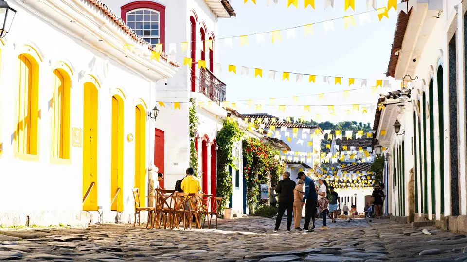 People walking on a cobblestone street in Paraty lined with white colonial buildings